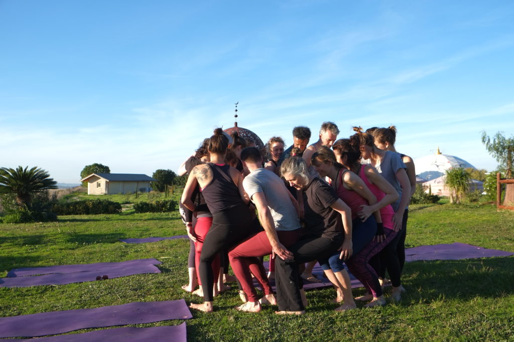 Stand in a circle and sit down on each other's laps. Acro-yoga!