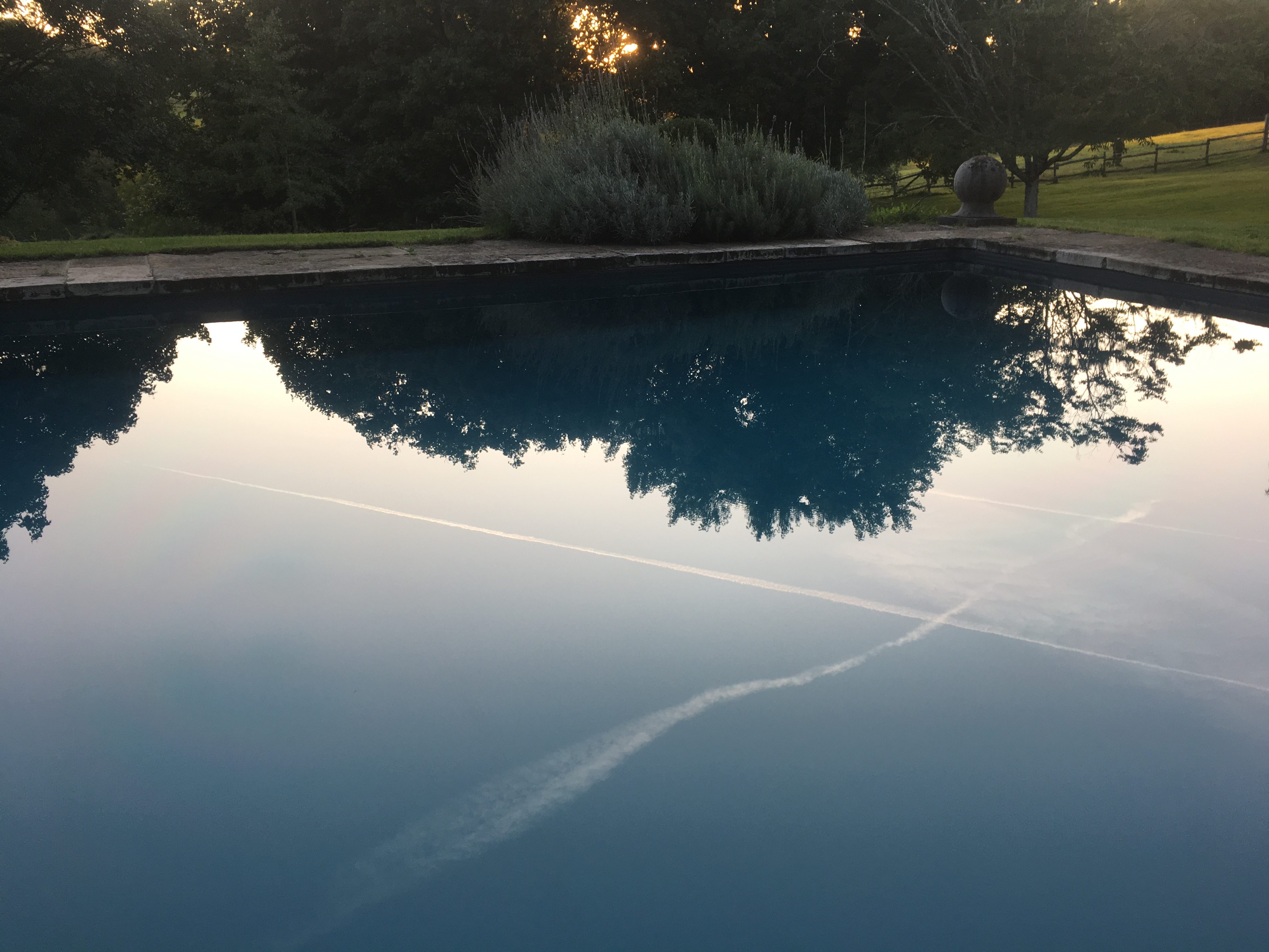 Flight trails from opposite directions cross reflected in the pool