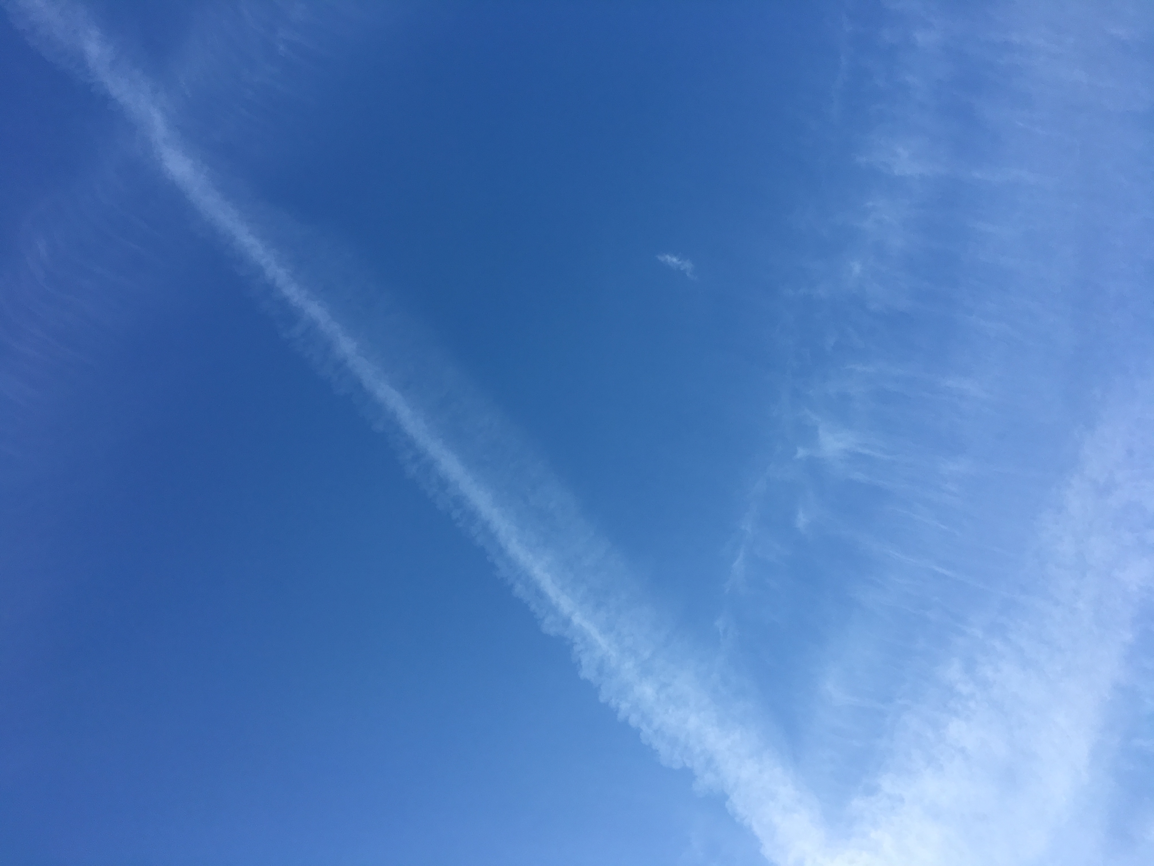 Two bands of contrails across a blue sky